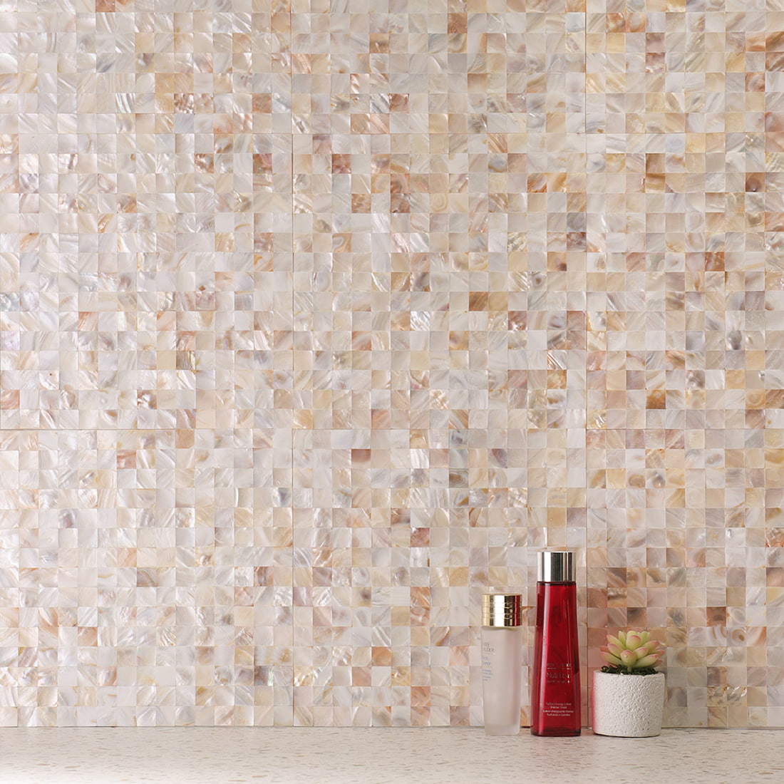 Installed cream white mother of pearl mosaic wall with bottles on countertop