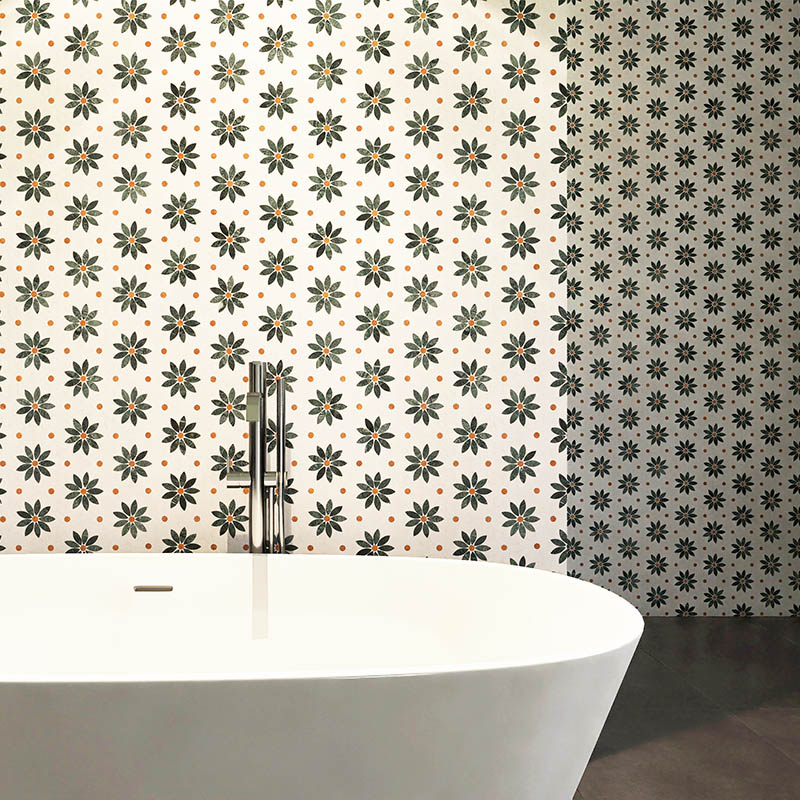 Green daisy wall tiles behind a modern white bathtub in a bathroom