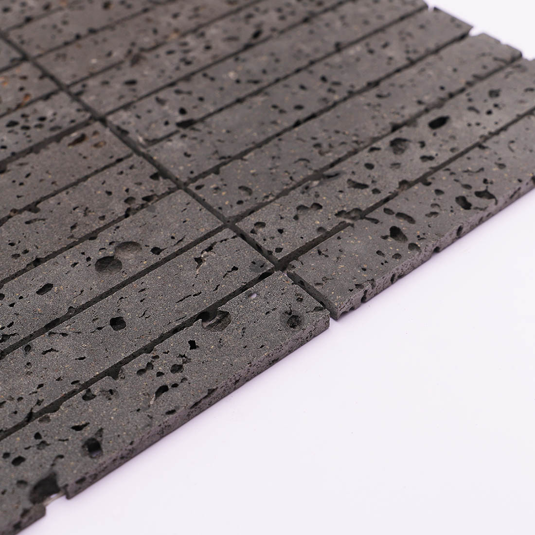 Side edge detail of dark gray lava stone stacked mosaic tile with natural texture
