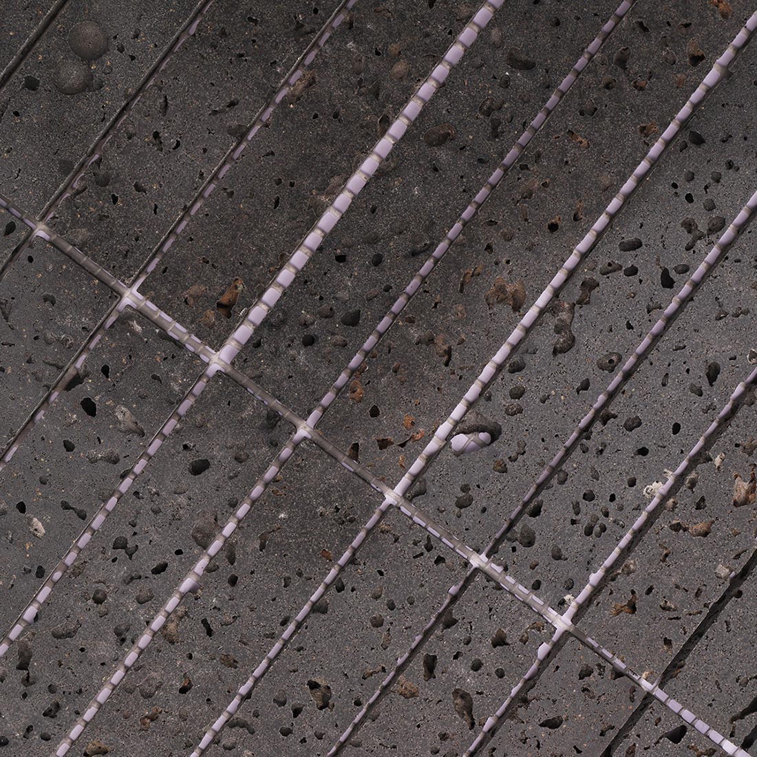 Close-up of dark gray lava stone stacked mosaic tiles with porous texture