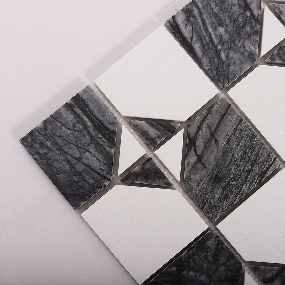 Angled close up of dark gray marble and white square mosaic showing corner details