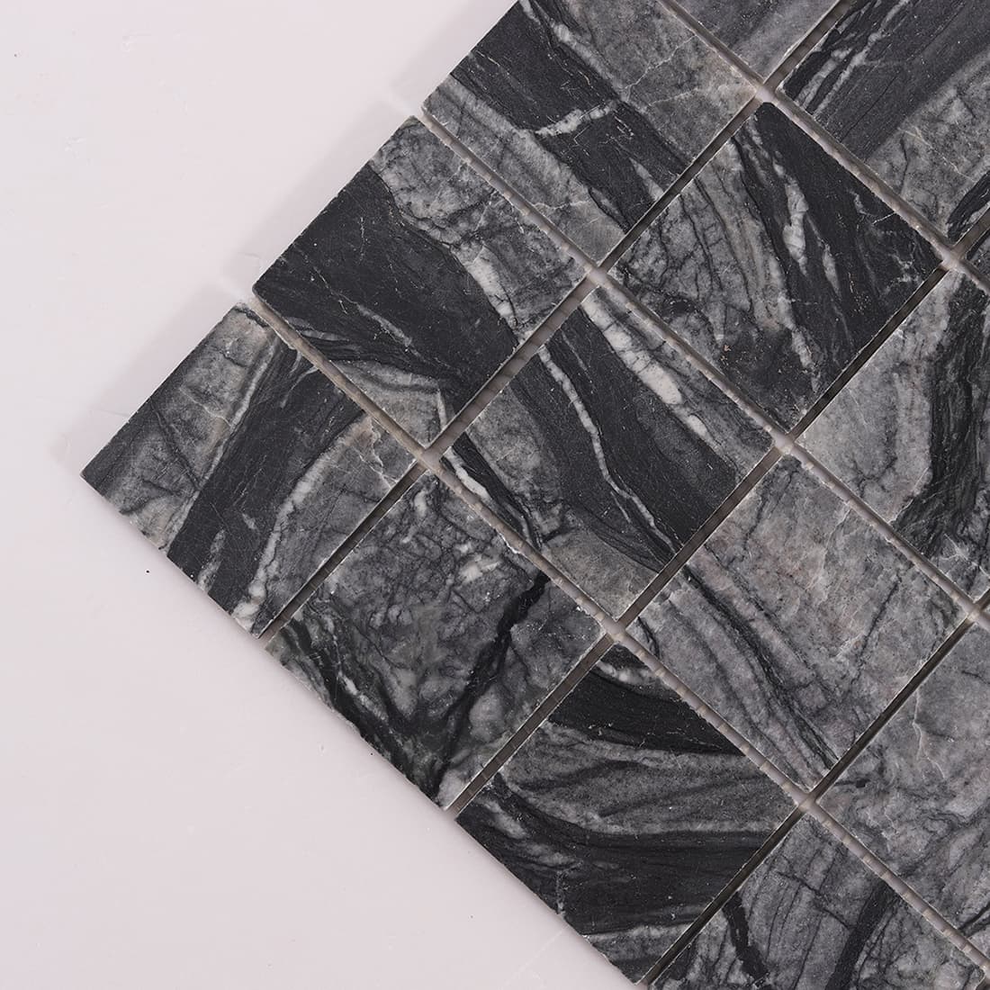 Corner close up of dark gray marble square mosaic tile with bold stone veining