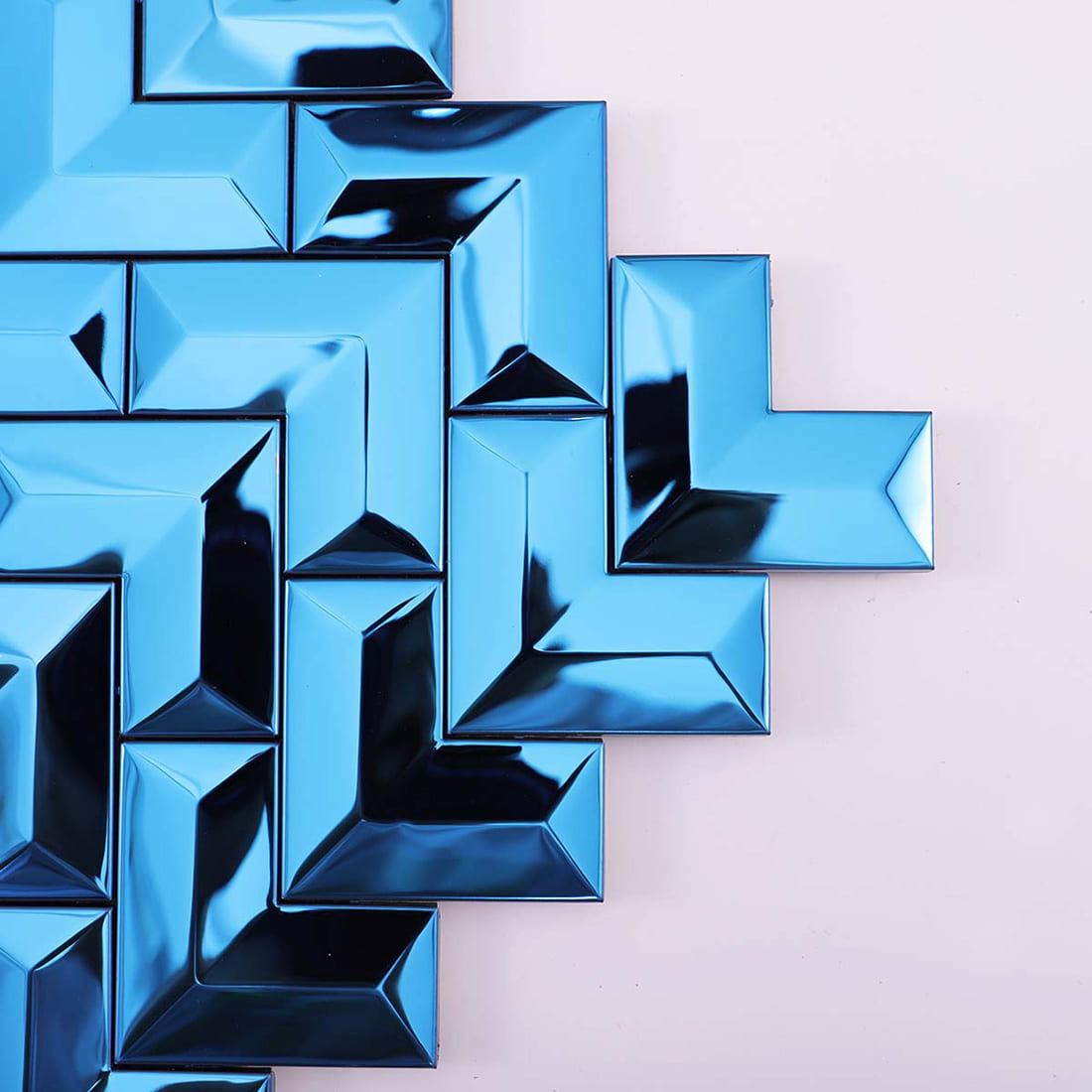 Close-up detail of the edges and corner of a blue chevron metal mosaic tile sheet.