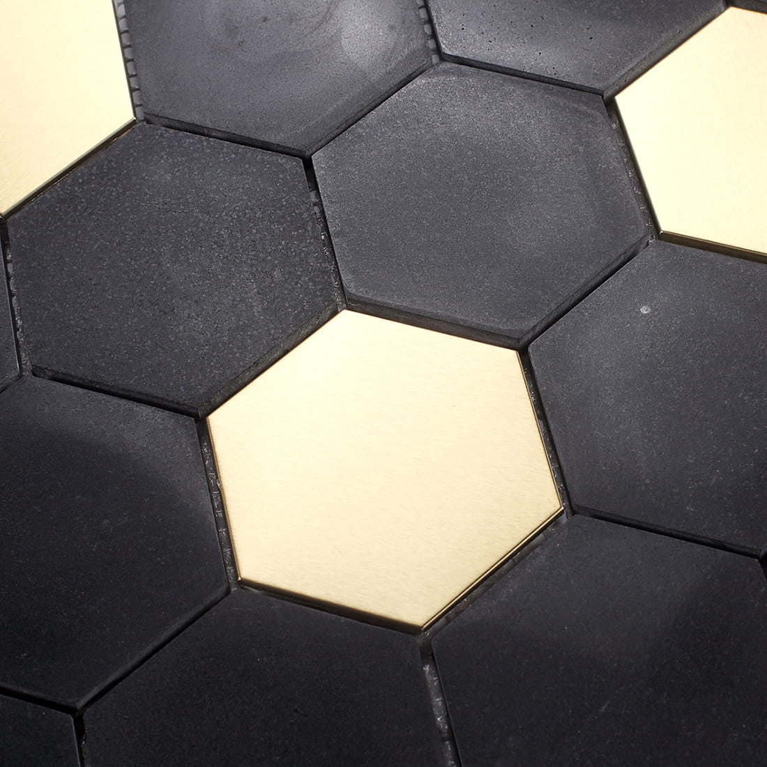 Macro detail of matte black and reflective gold hexagonal mosaic tile surfaces.