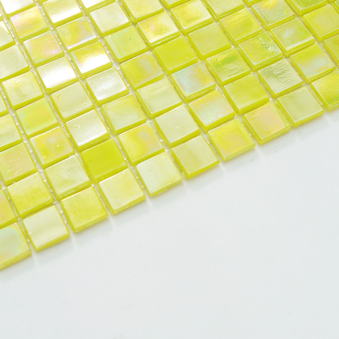 Edge close-up of pearlescent lime yellow glass mosaic tiles showing thickness and sheen