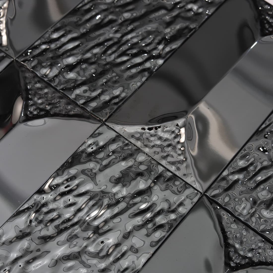 3D faceted black stainless steel tiles with a metallic shine.
