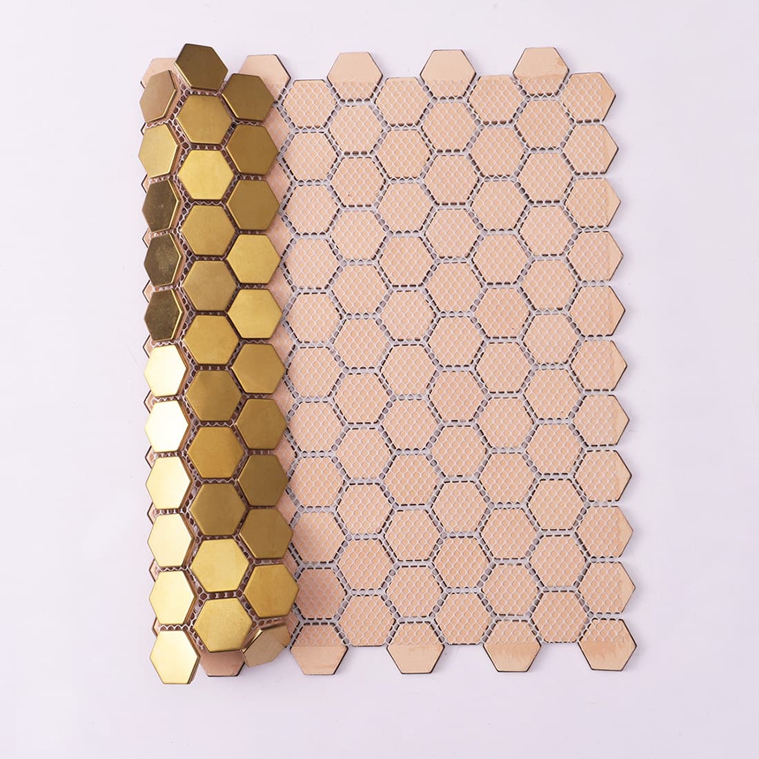 Rear view of a gold hexagon mosaic tile sheet showing the white fiber mesh backing.