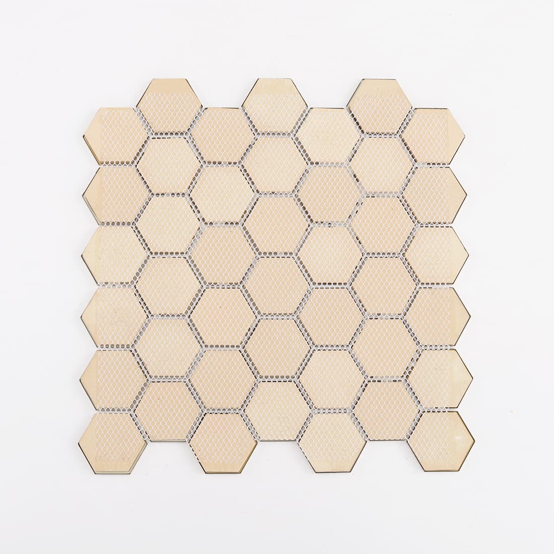 Rear view of a large gold hexagon mosaic tile sheet showing the white fiber mesh backing.