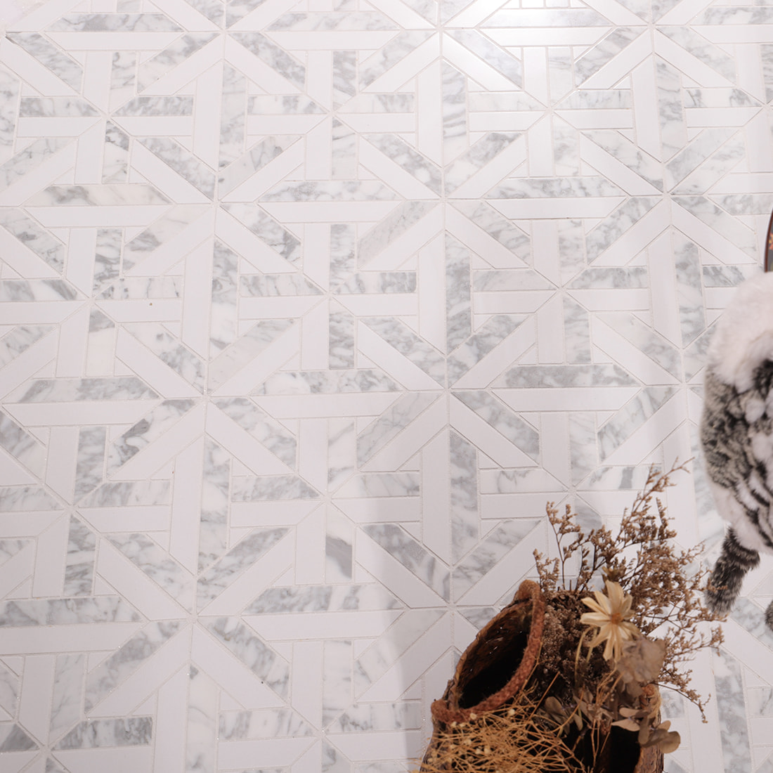 Installed Carrara marble geometric mosaic surface with repeating pattern and decor