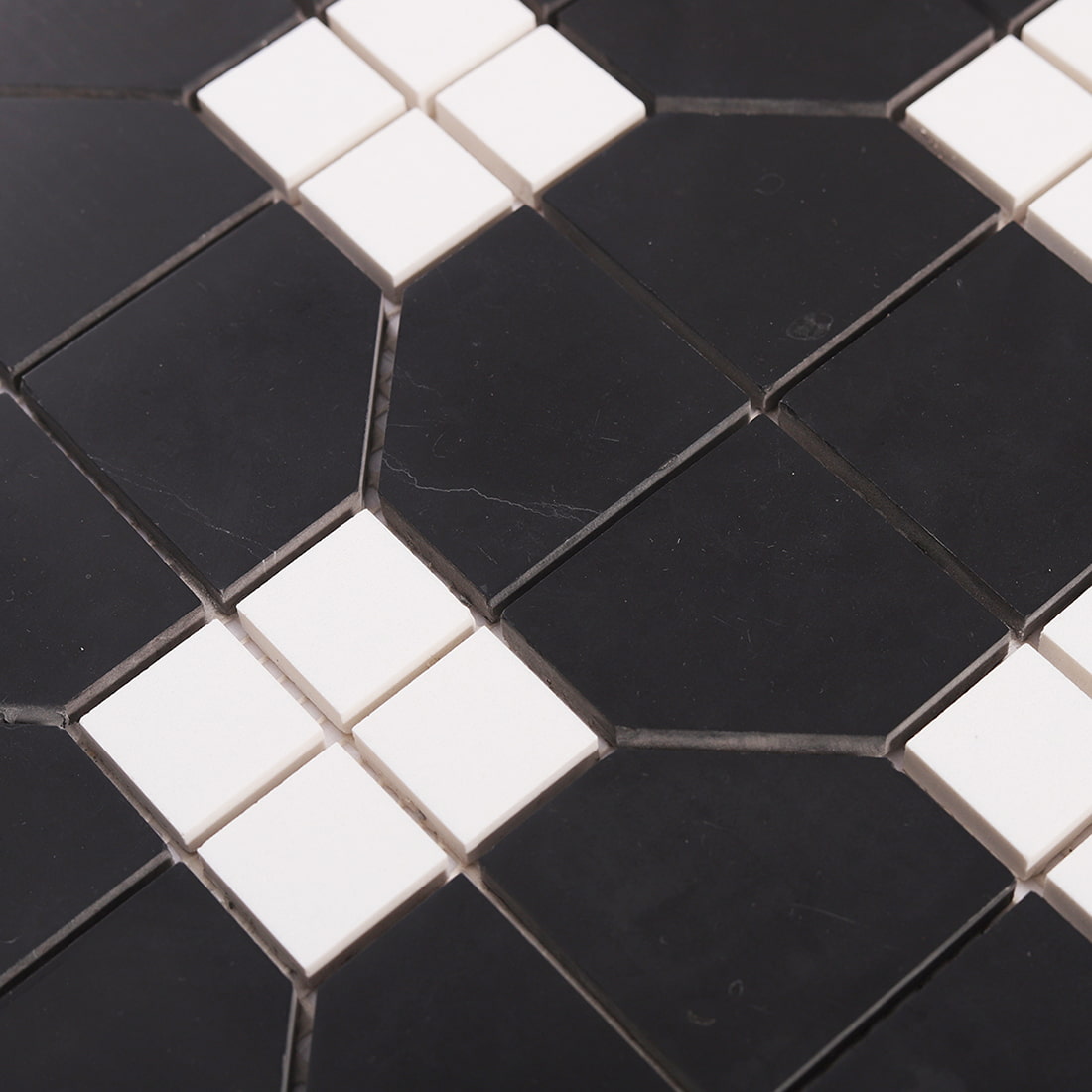 Close-up of geometric marble mosaic tile showing black stone texture