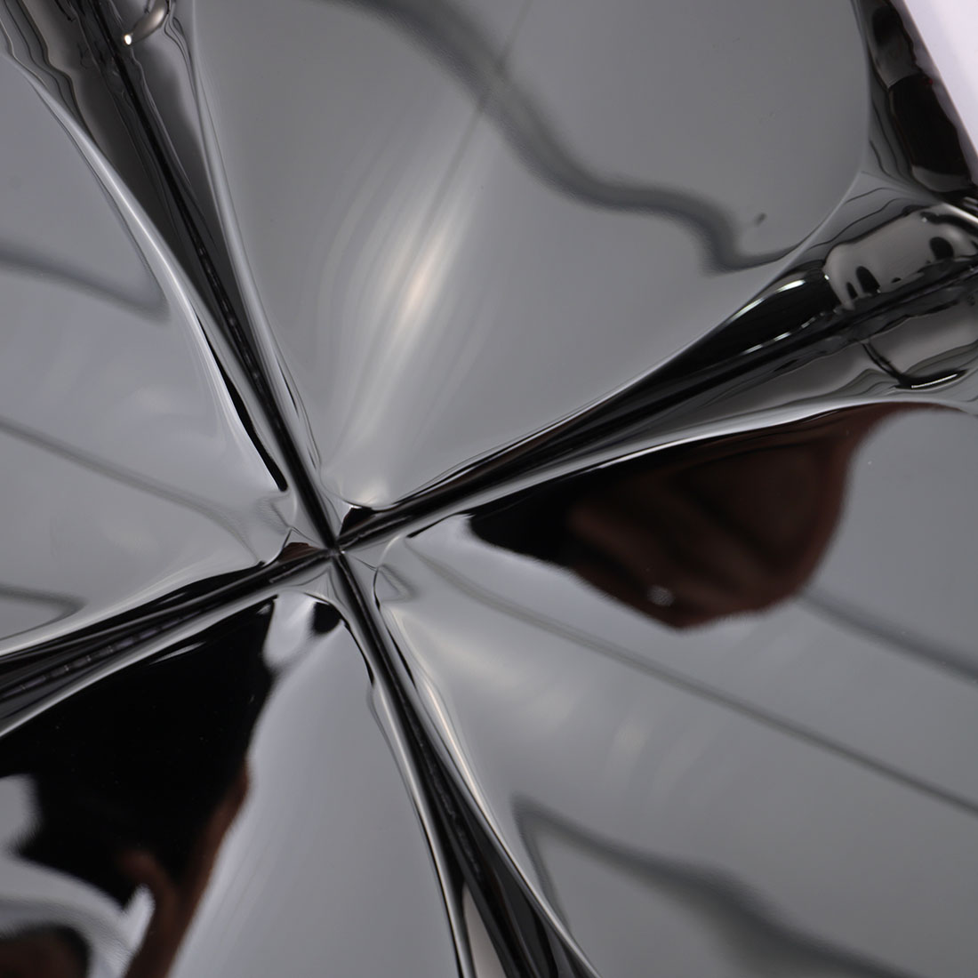 Close-up of sculpted square surfaces on glossy black stainless steel mosaic tiles