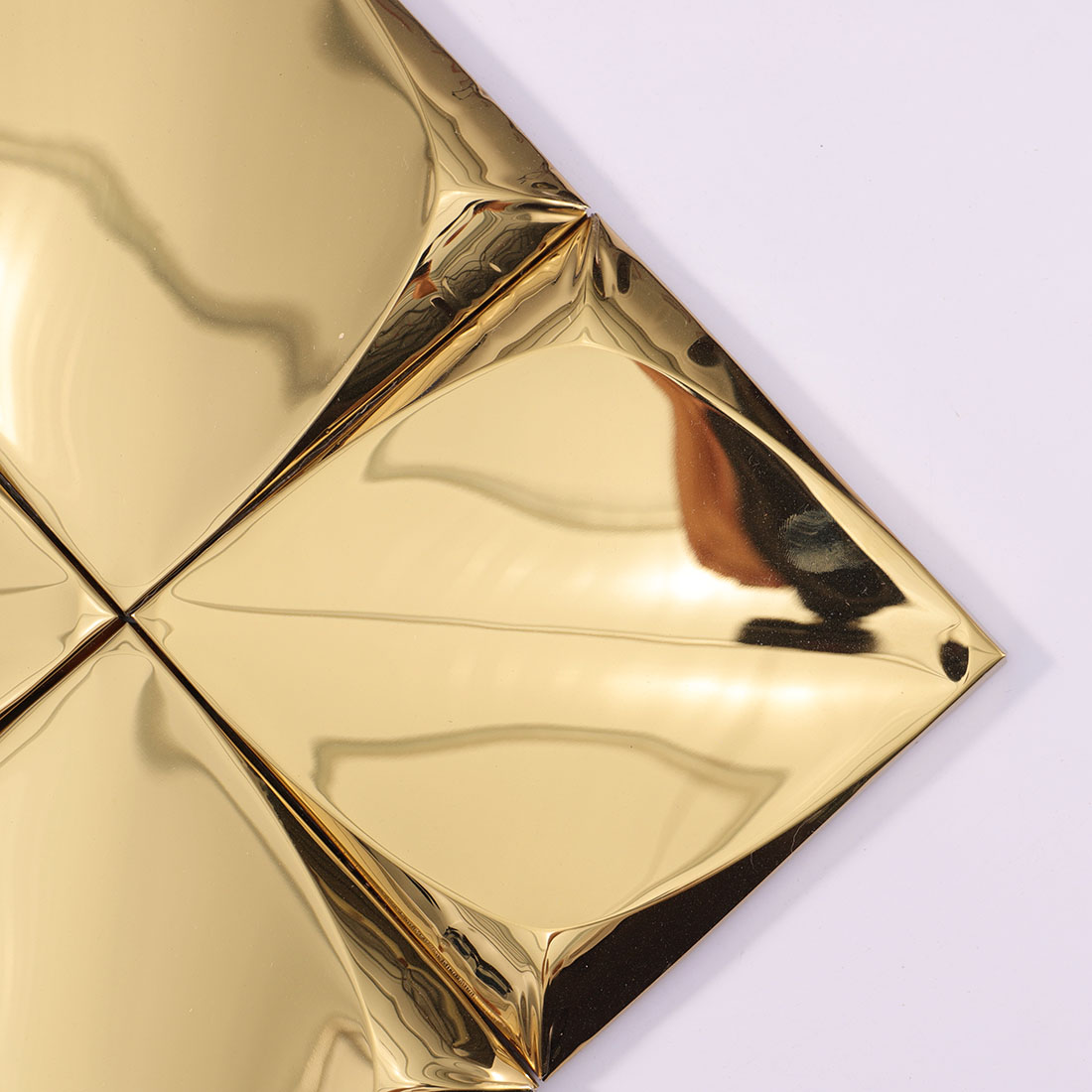 Close-up of a gold 3D square stainless steel tile corner with reflective surface