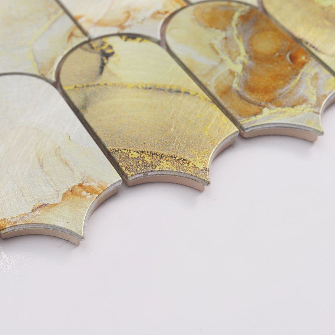 Edge detail of gold cream curved aluminum mosaic tile with layered thickness