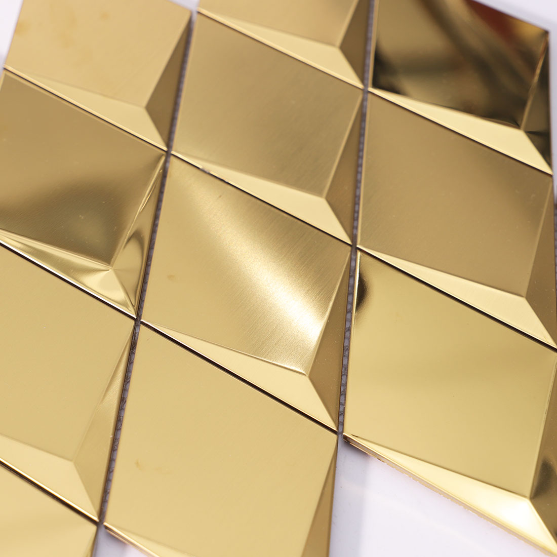 Close-up of gold geometric metal mosaic tiles with brushed texture