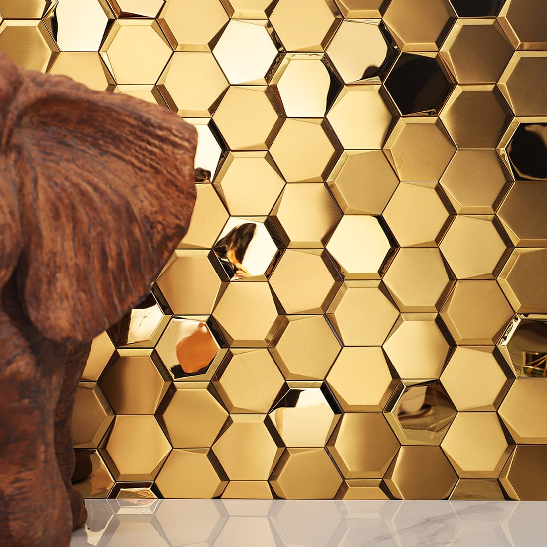 Full view of a luxury gold hexagon mosaic backsplash behind a marble counter.