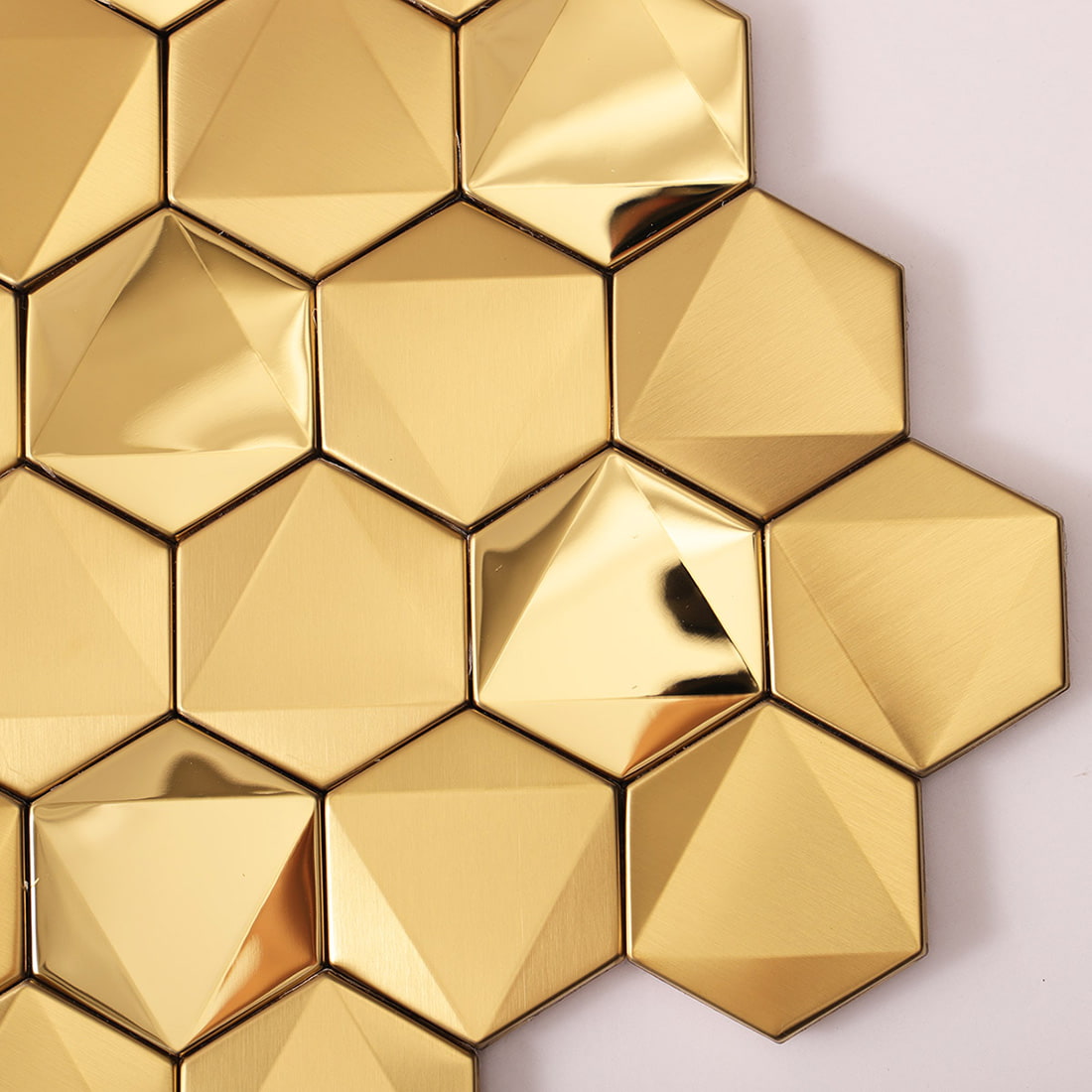 Close-up of faceted gold hexagon tiles showing brushed and glossy surfaces.
