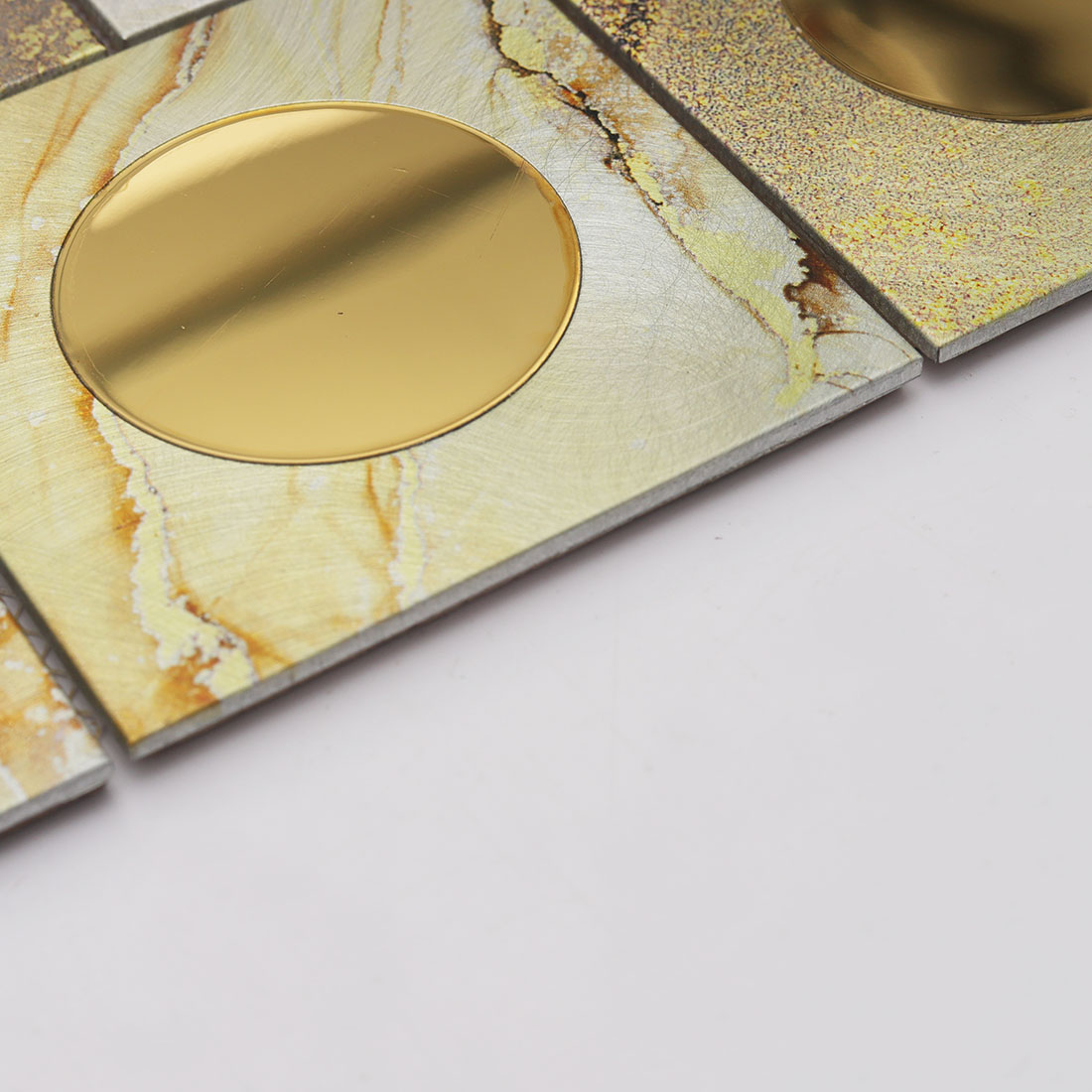 Edge detail of gold mirror round glass on cream aluminum mosaic tile