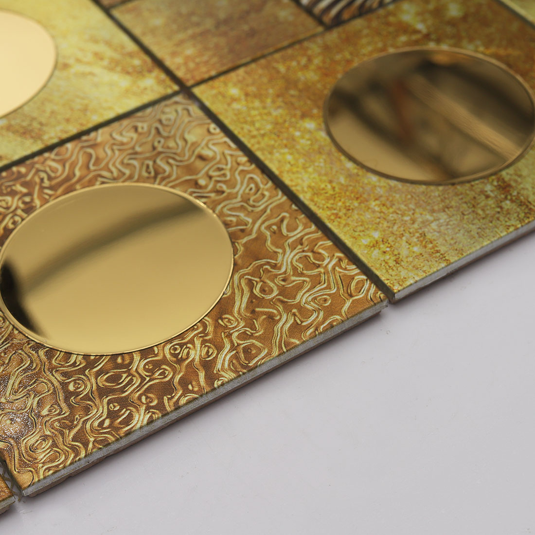 Edge detail of gold round mirror glass and textured aluminum mosaic tile