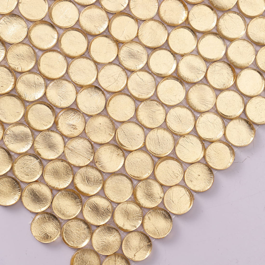 Close up of gold penny round glass mosaic tiles with metallic finish