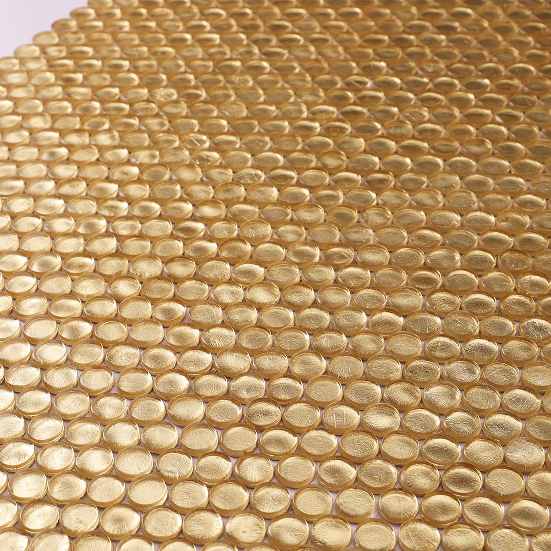 Angled view of gold penny round glass mosaic tile sheet