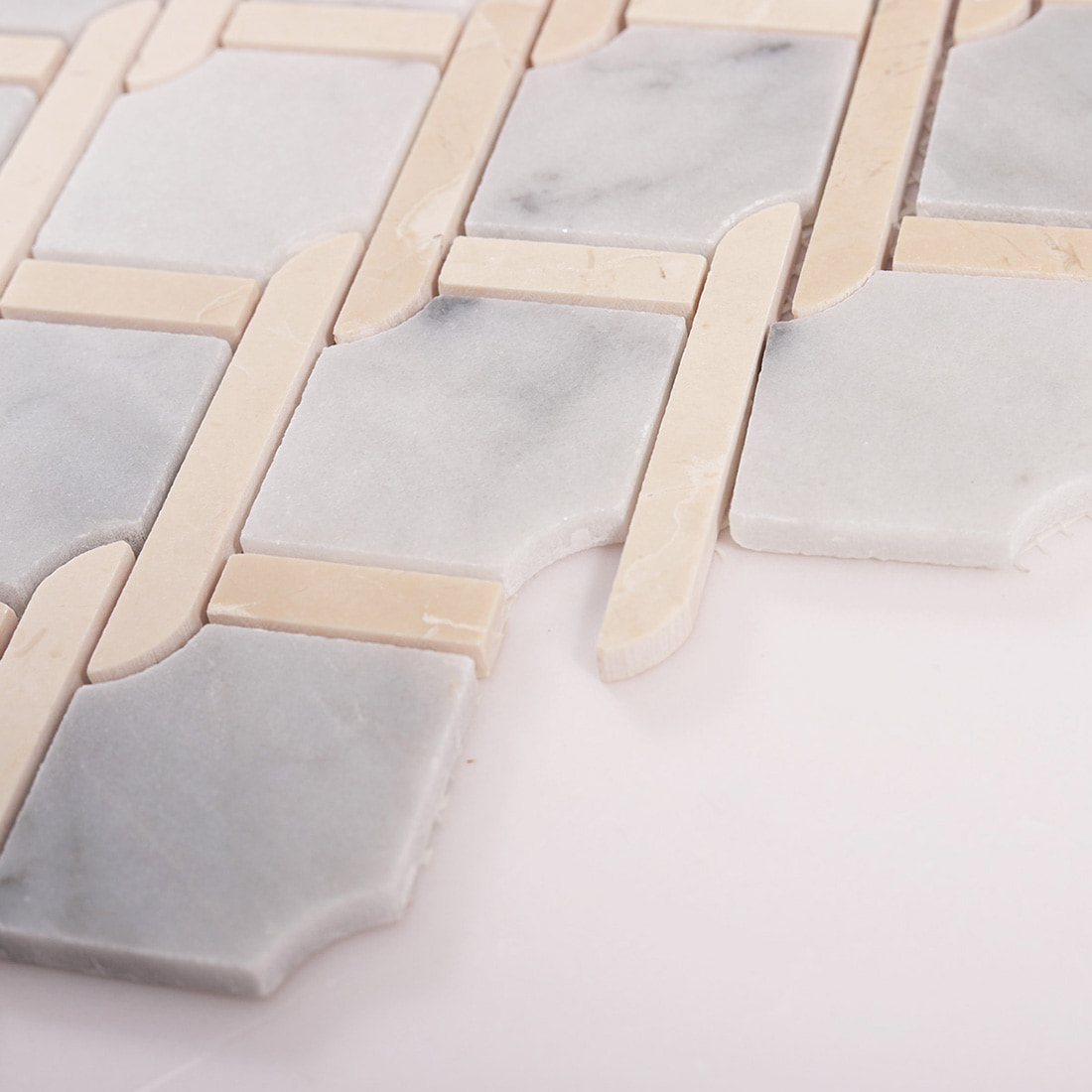 Angled close up showing thickness of gray marble and beige chain link mosaic tiles