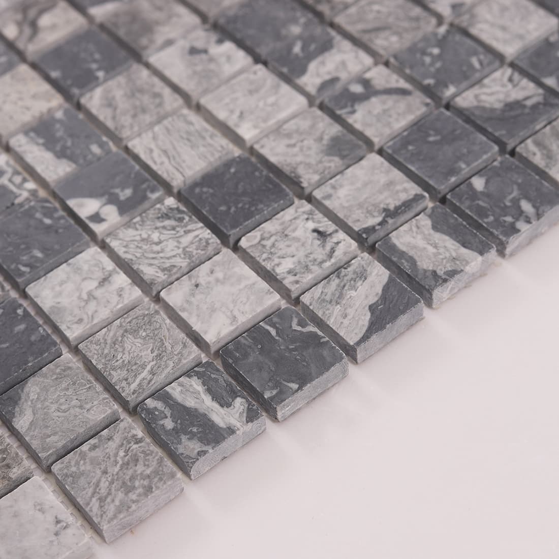 Edge detail of gray marble square mosaic tiles with layered stone look