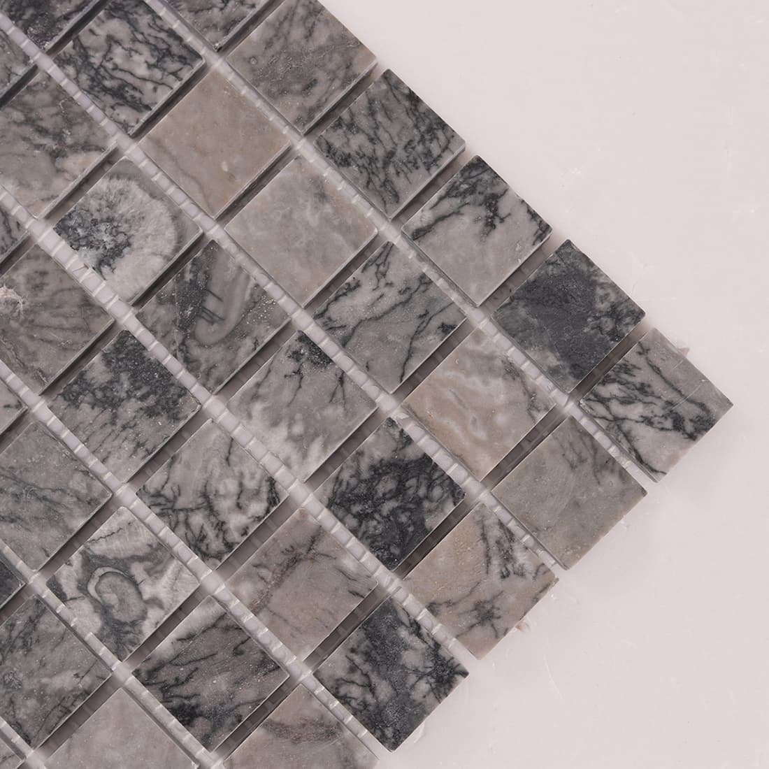 Corner detail of gray marble square mosaic tiles with visible grout joints