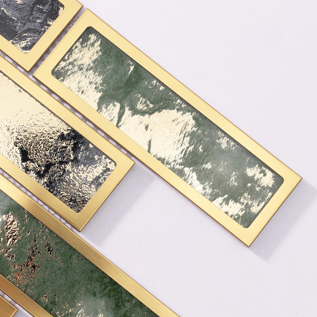 Close-up of green and black mosaic tiles with brushed gold rectangular frames