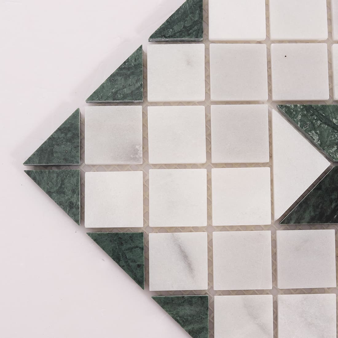 Corner detail of green marble and Carrara white mosaic tile with triangular pieces