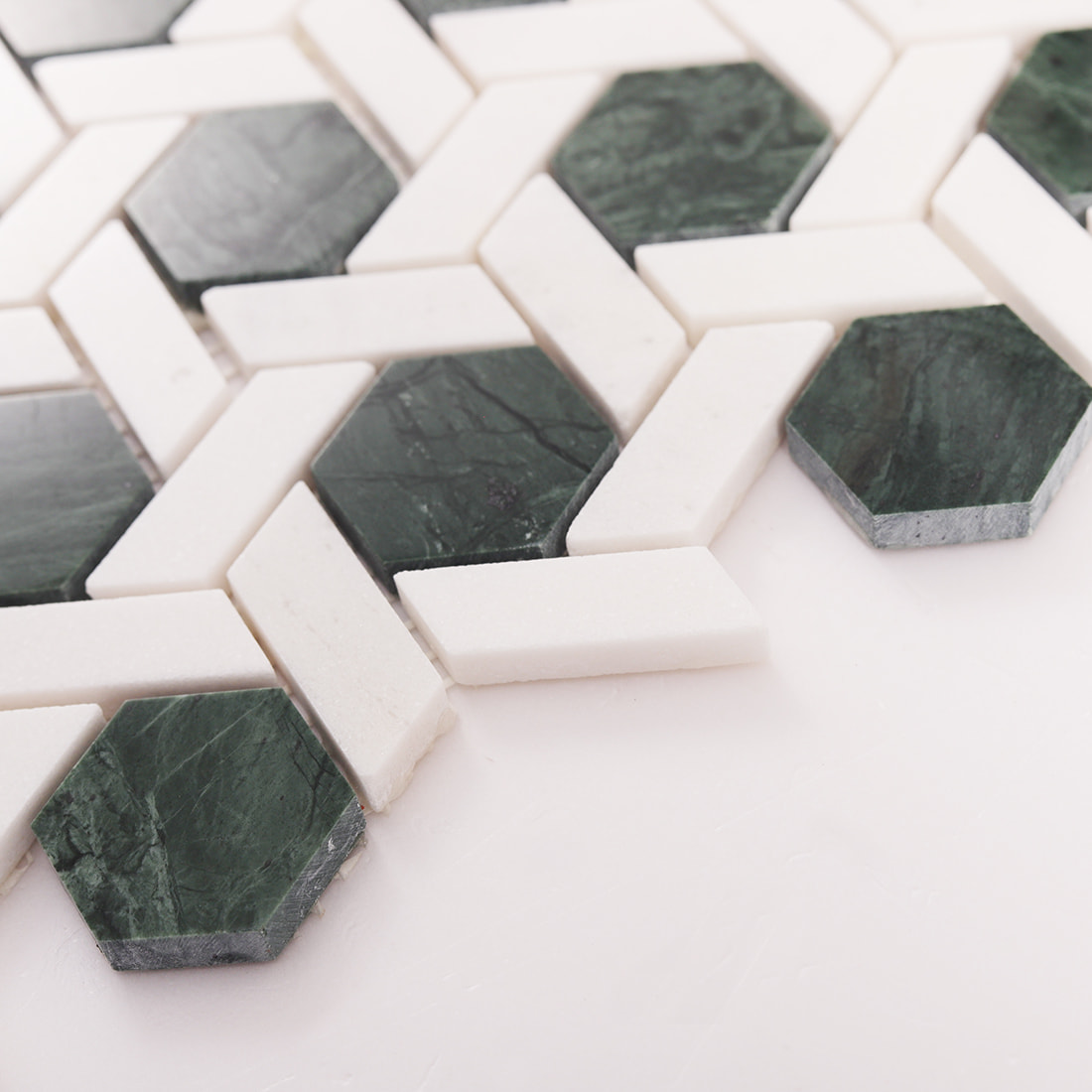 Angled close up of green hexagon weaved marble mosaic tile pieces and grout gaps