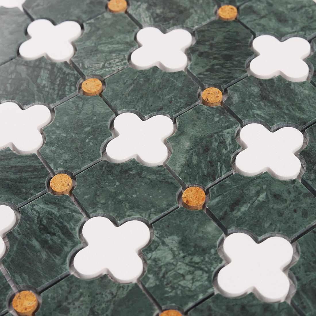 Angled close up of green marble mosaic with white clover shapes and gold dot details