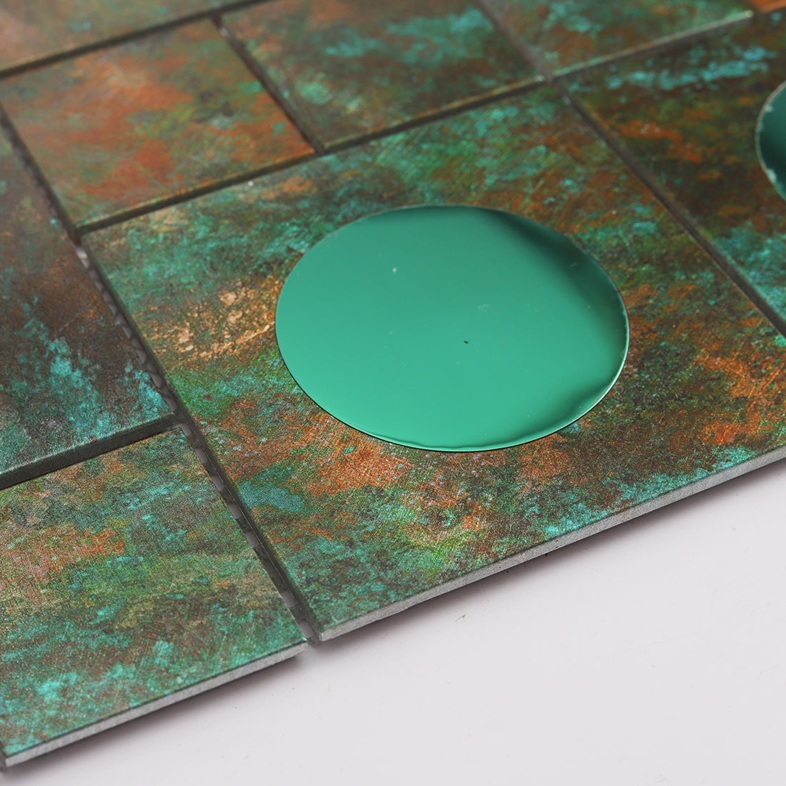 Edge detail of green mirror glass and aged verdigris aluminum mosaic tile