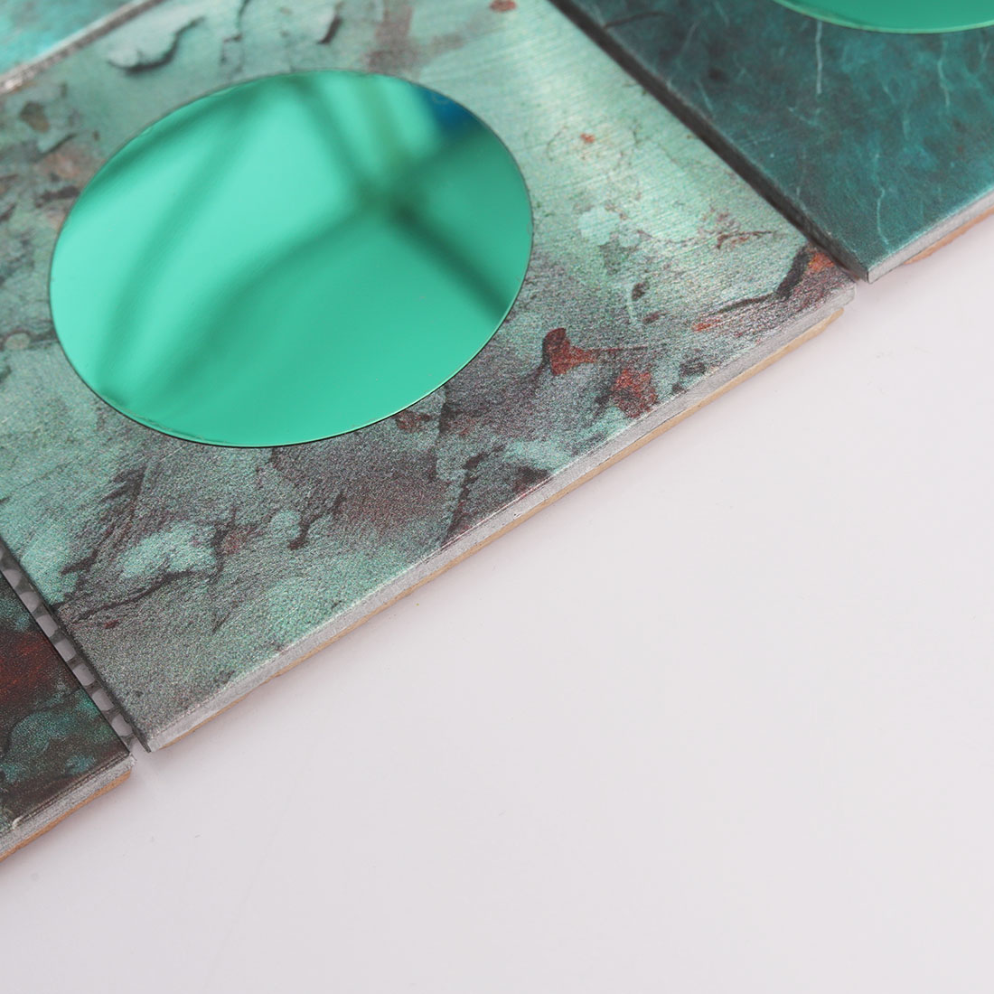 Edge detail of green round mirror glass and textured aluminum mosaic tile