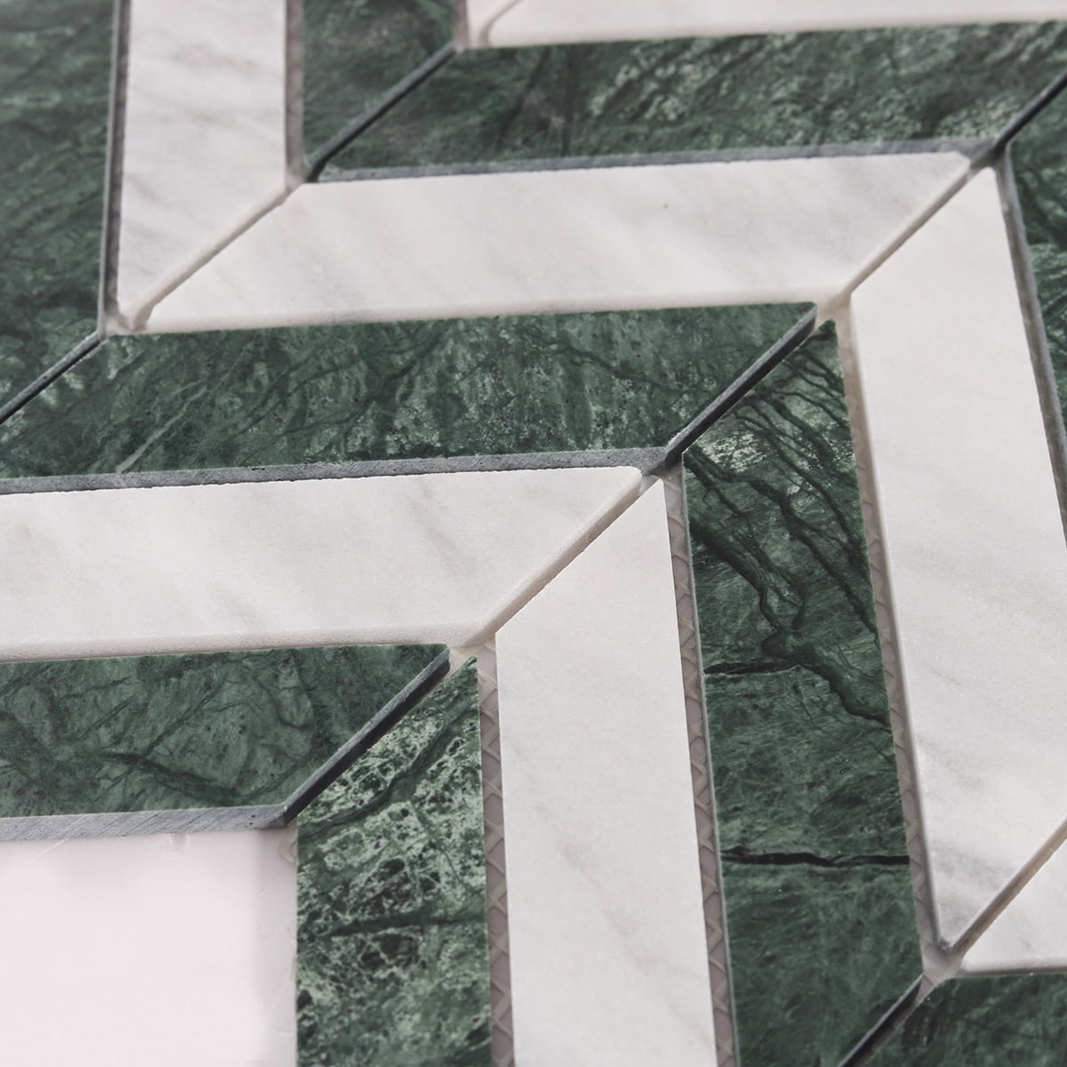 Close-up of green and white marble chevron pieces and grout gaps