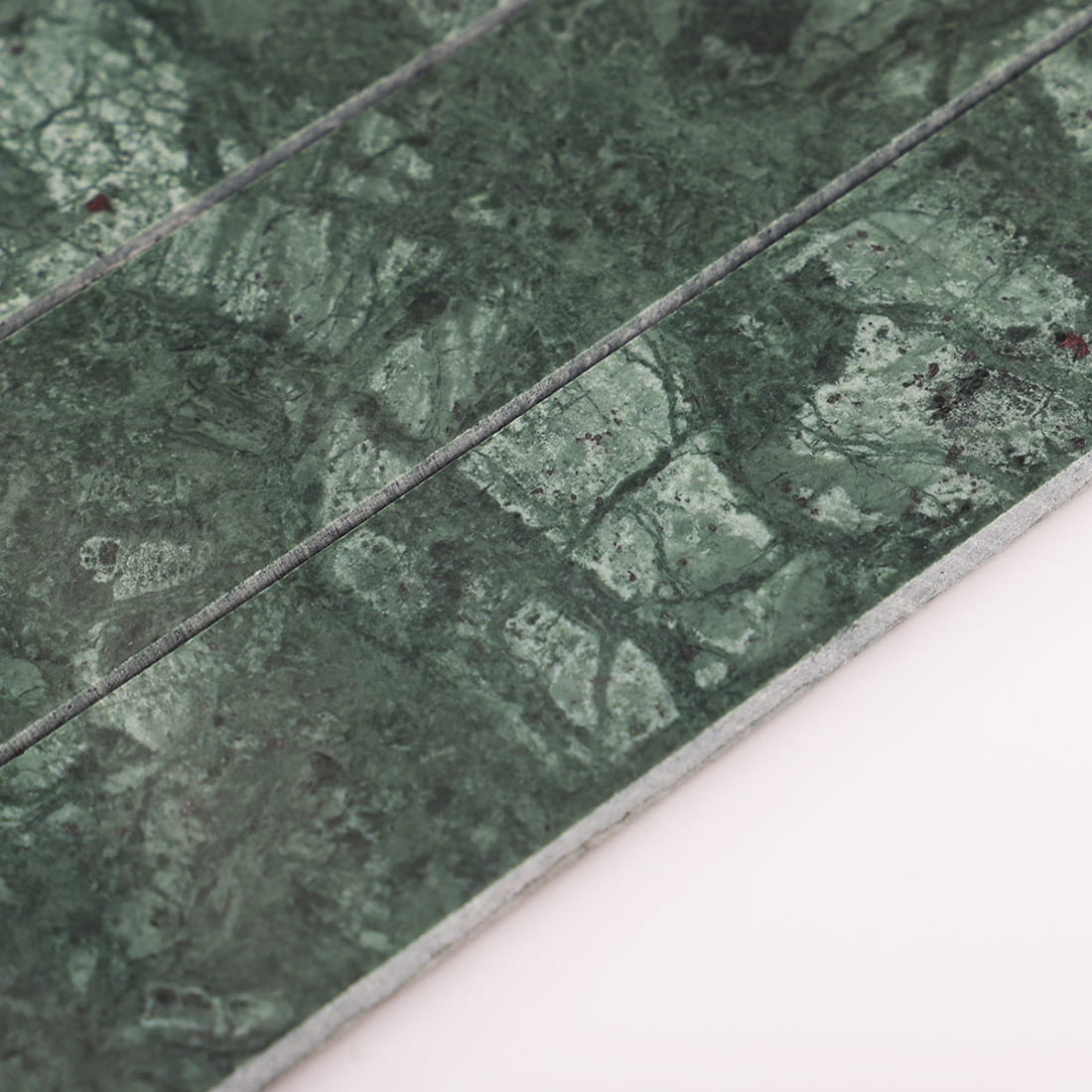 Side closeup of green marble mosaic showing thickness and strip gaps on white background
