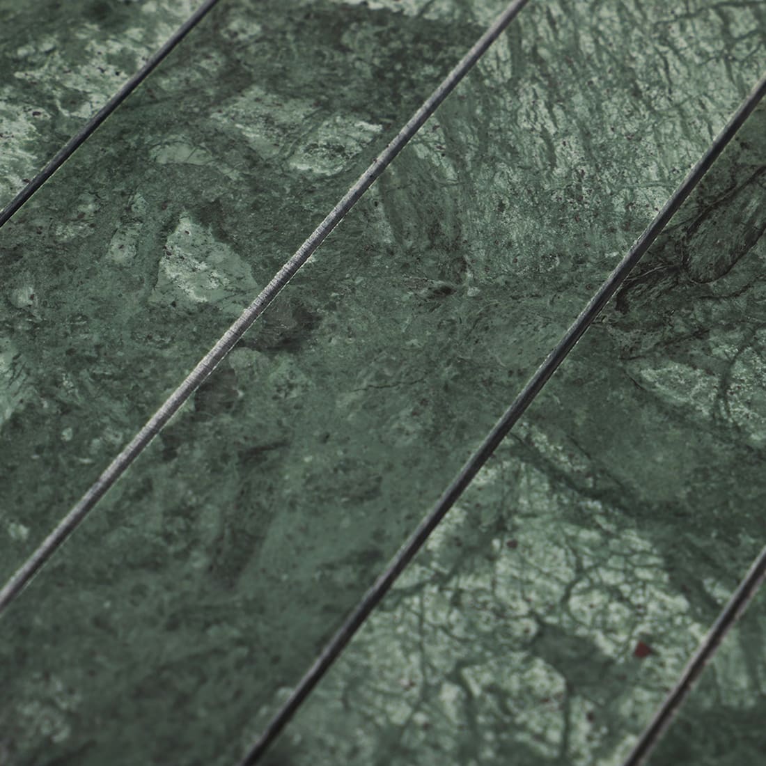 Closeup of green marble mosaic surface with long strip lines and natural pattern variation