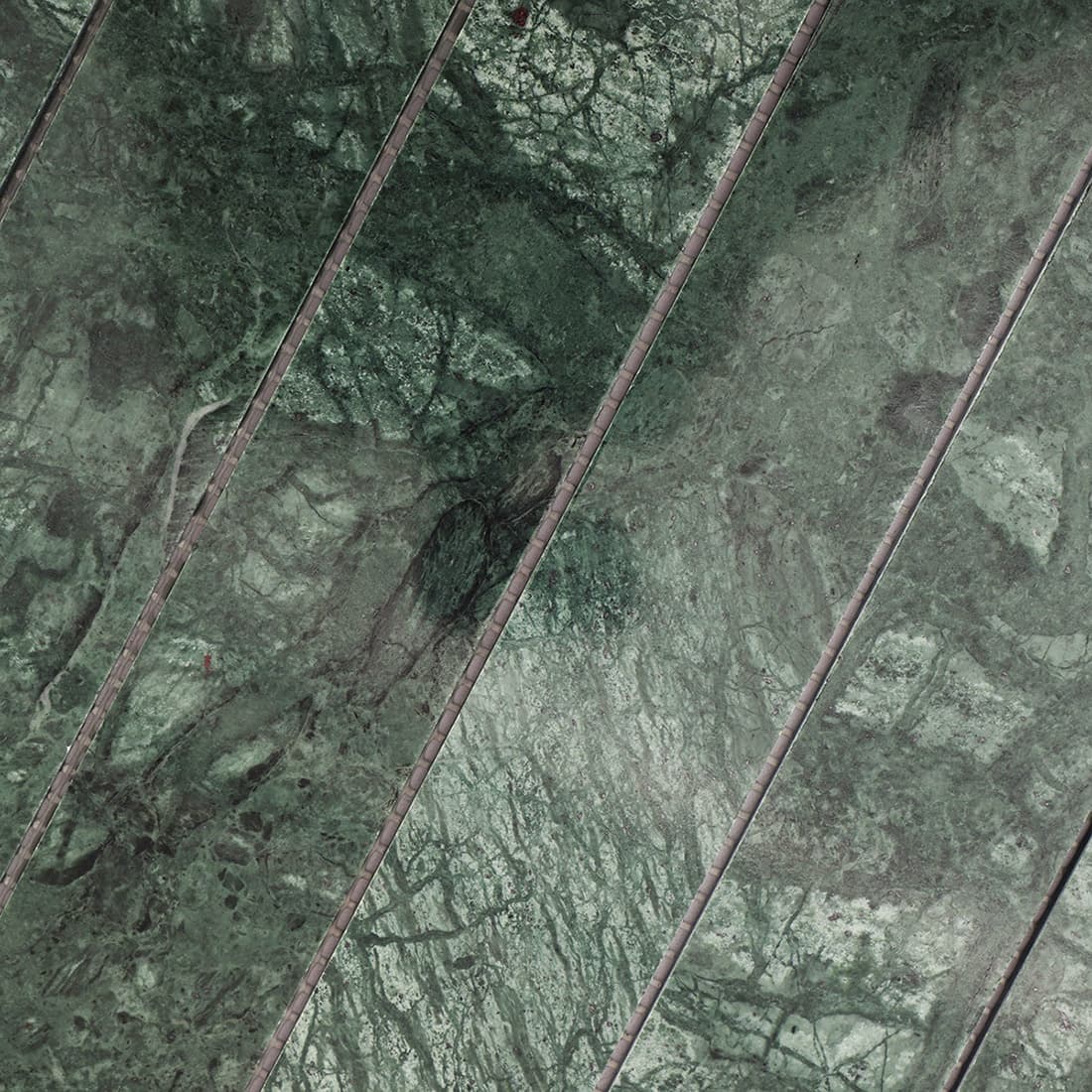 Closeup of green marble linear mosaic showing natural veining and surface texture