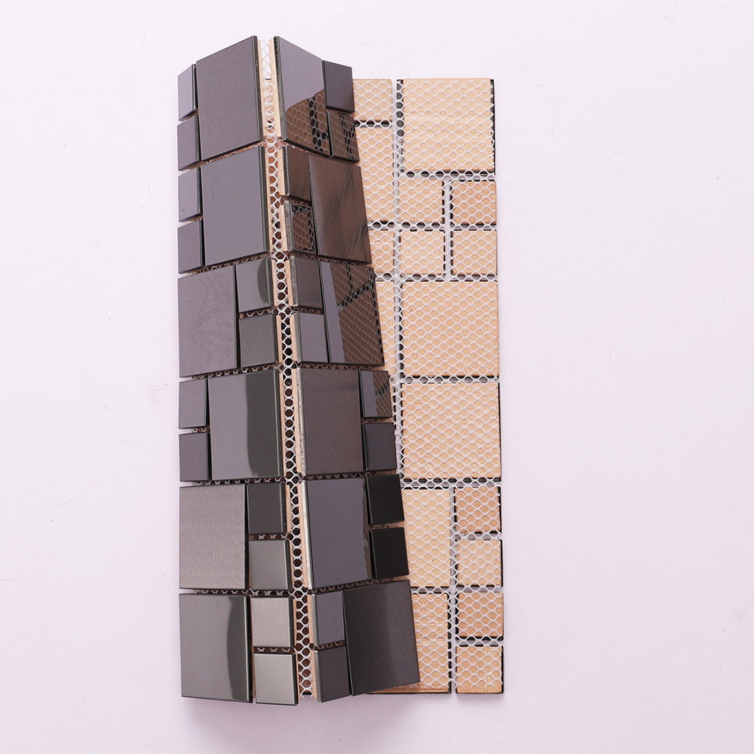 Rolled gunmetal mosaic tile sheet showing white fiber mesh backing.