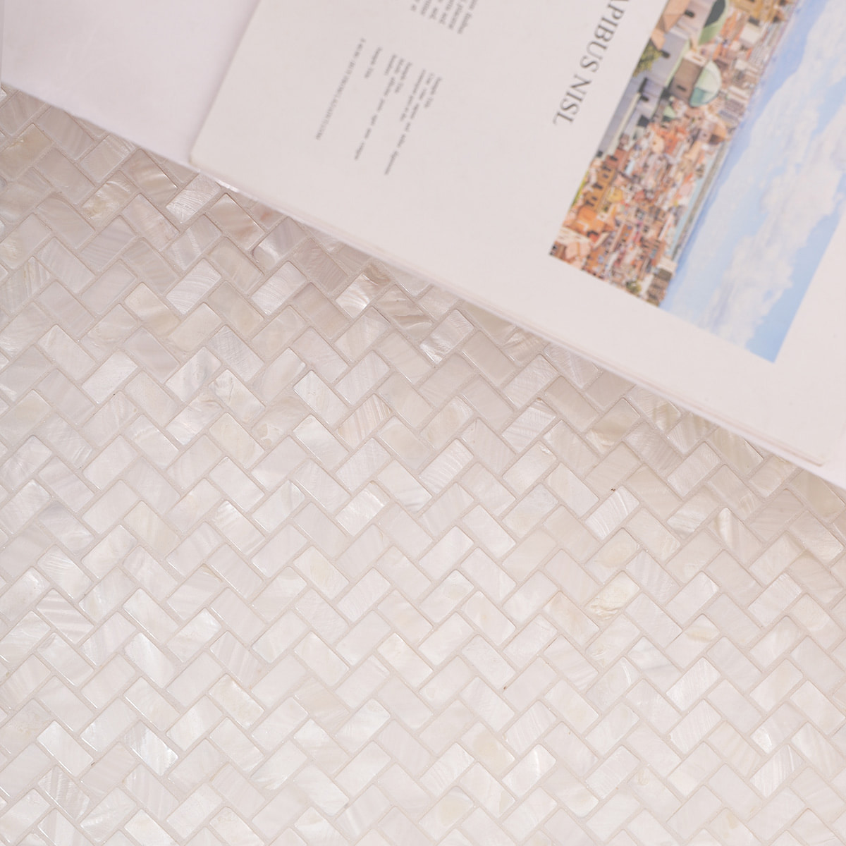 Close view of installed herringbone mosaic wall with a book in the foreground