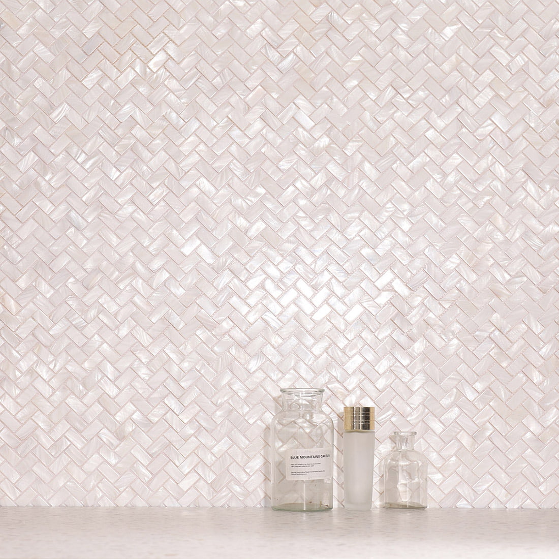 Installed herringbone mother of pearl mosaic wall with decorative bottles