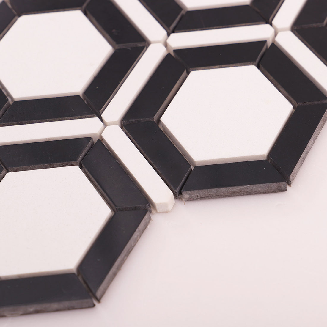 Close up showing edge thickness of black and white hexagon frame tile pieces