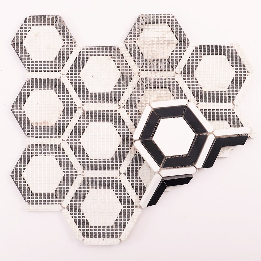 Back view of mosaic tile sheet on mesh with one loose sample piece