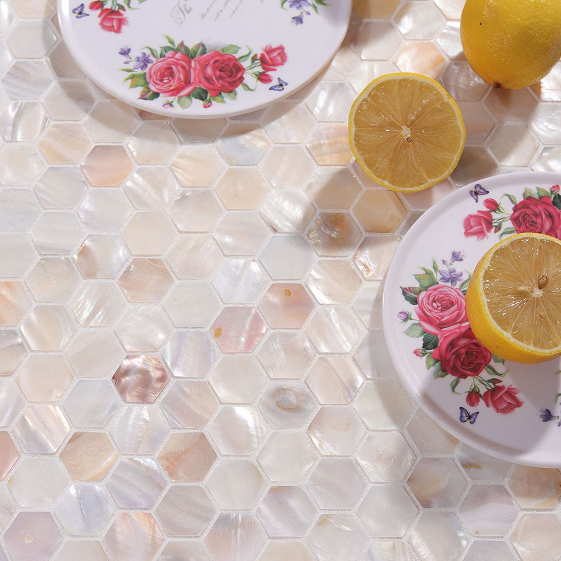 Closeup styling shot of hexagon mosaic tile with floral plate and lemon half