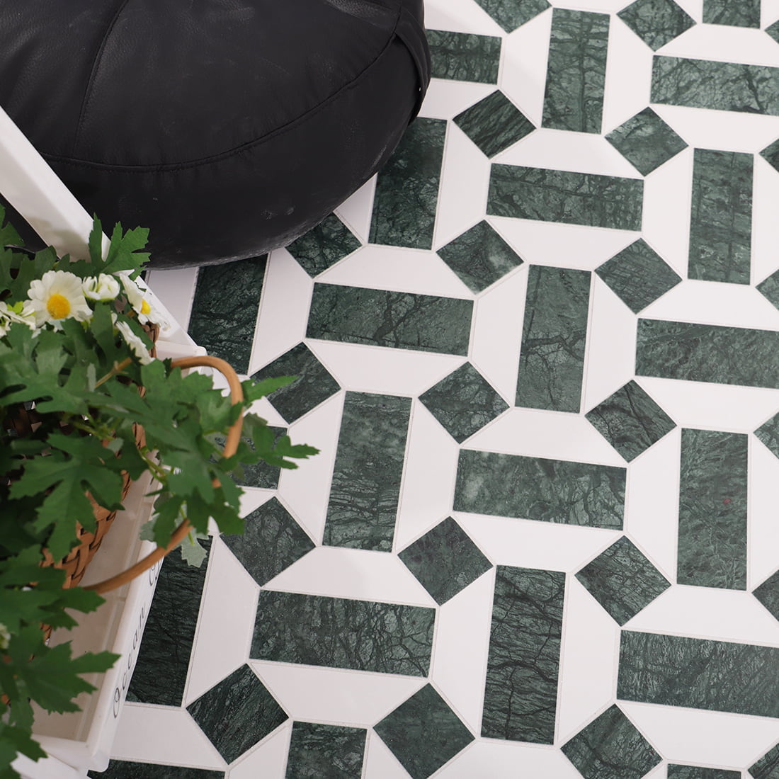 Installed green and white geometric marble mosaic floor with black pouf and plants