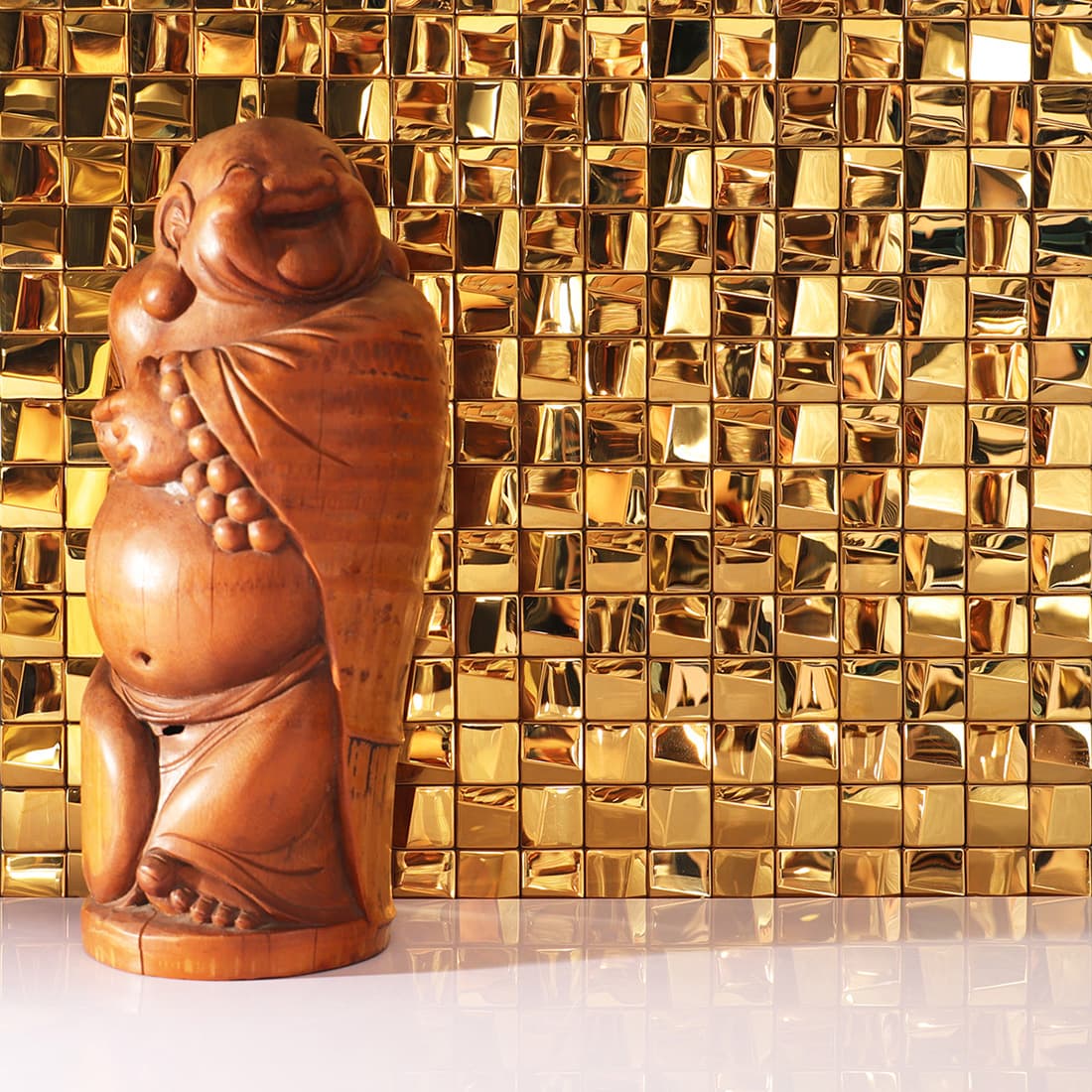 Gold 3D square mosaic tile feature wall with a wooden Buddha statue decoration.