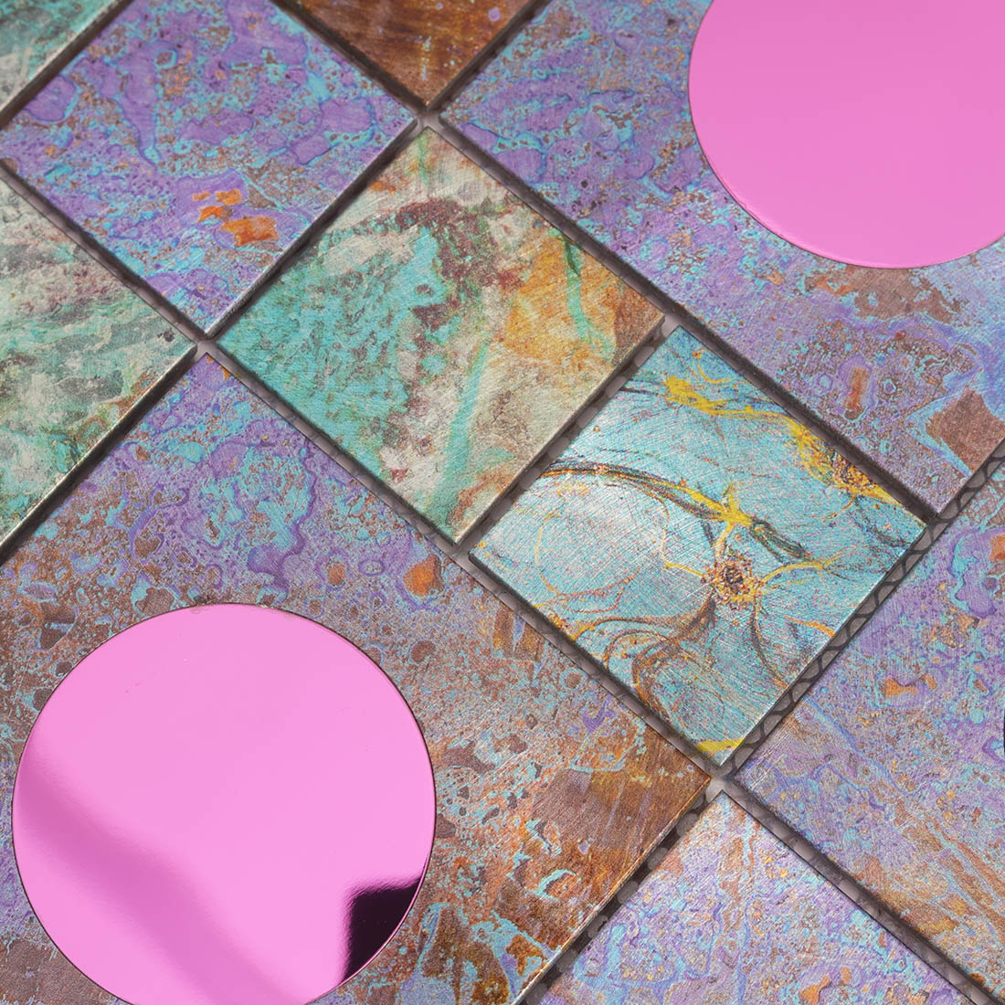 Iridescent metal mosaic tile with pink circular glass accents and textured finish