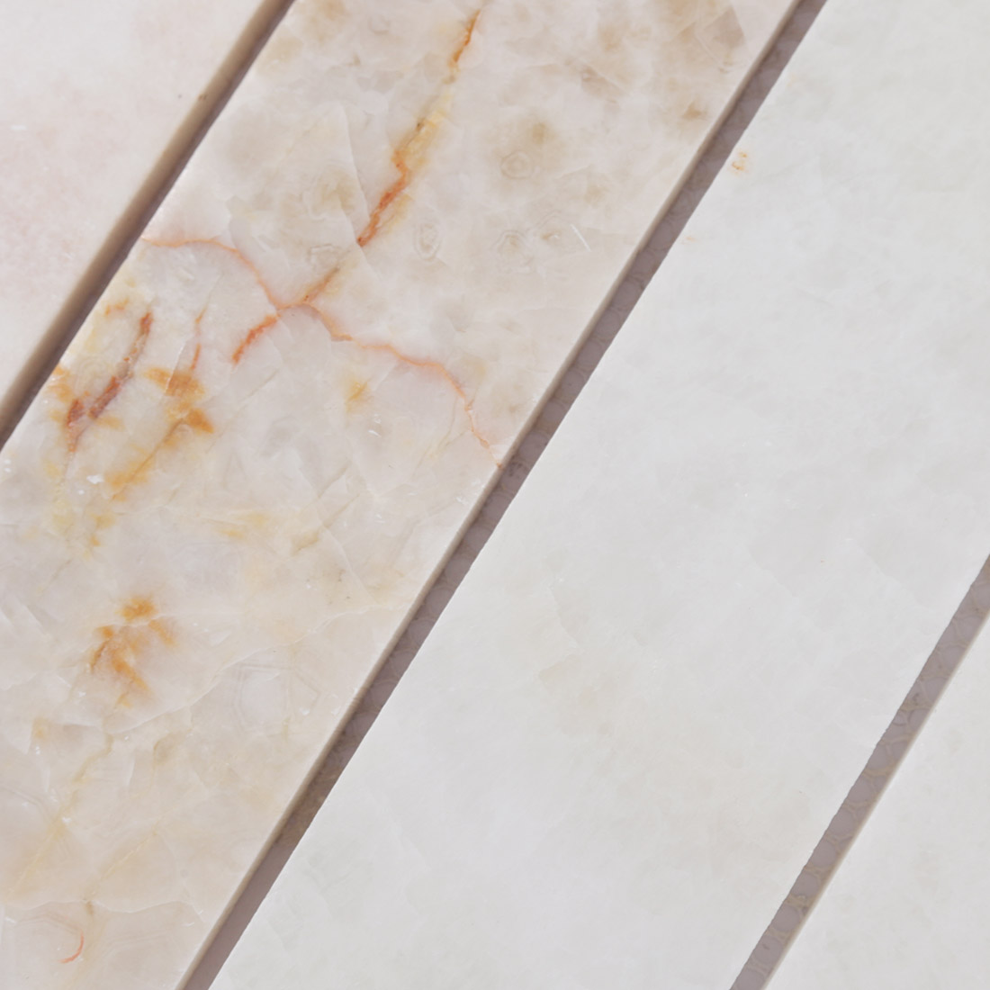 Close-up of ivory onyx mosaic strips with soft golden natural veining