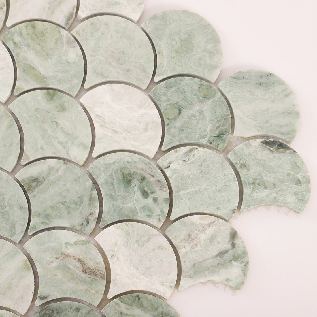 Corner close up of light green marble fish scale mosaic showing curved pieces and grout joints