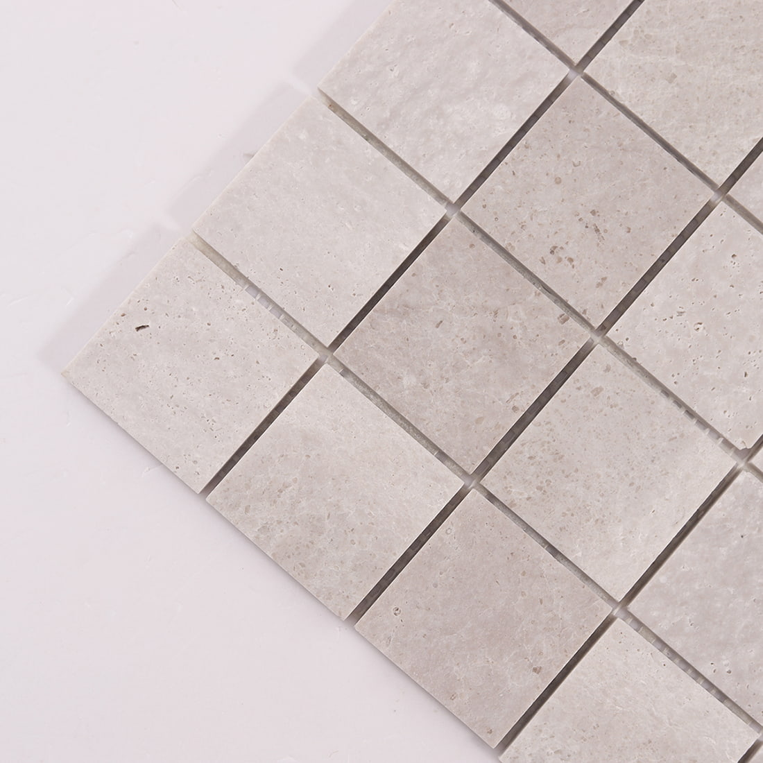 Corner detail of light gray marble square mosaic tiles with natural stone texture
