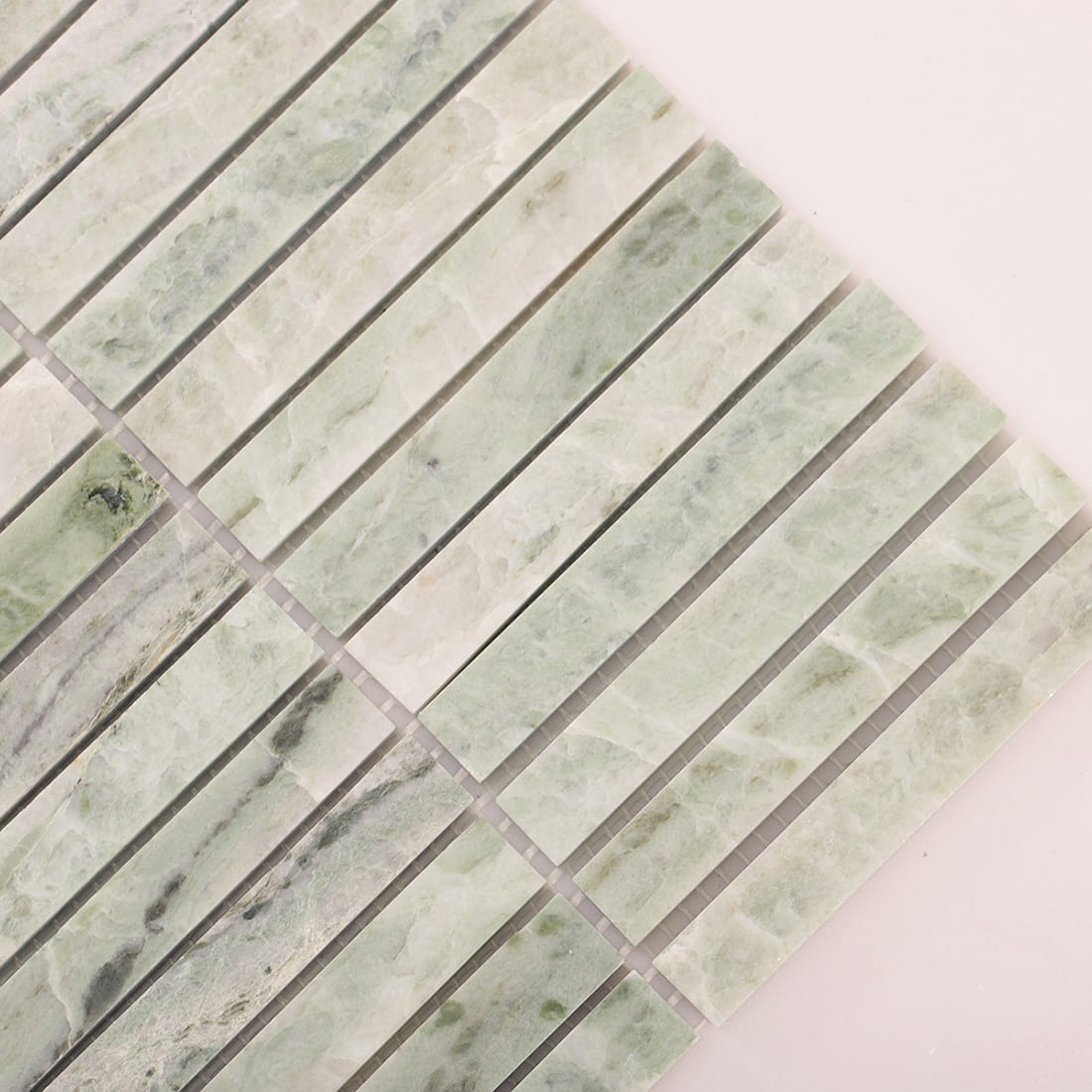 Angled closeup of light green marble mosaic strips showing edges and spacing